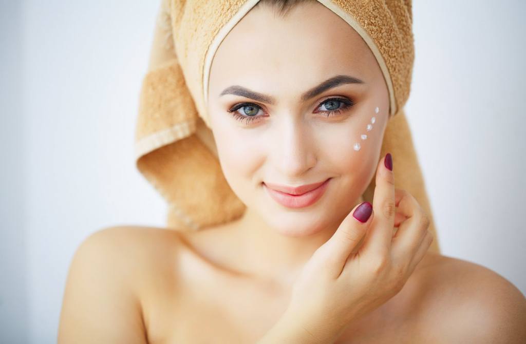 Beauty and Care. Portrait of a Girl with a Brown Towel on the Head. Young Woman With Pure Skin. Holds Cream in Hands. to Apply Cream for face. High Resolution مقاله آرایشی